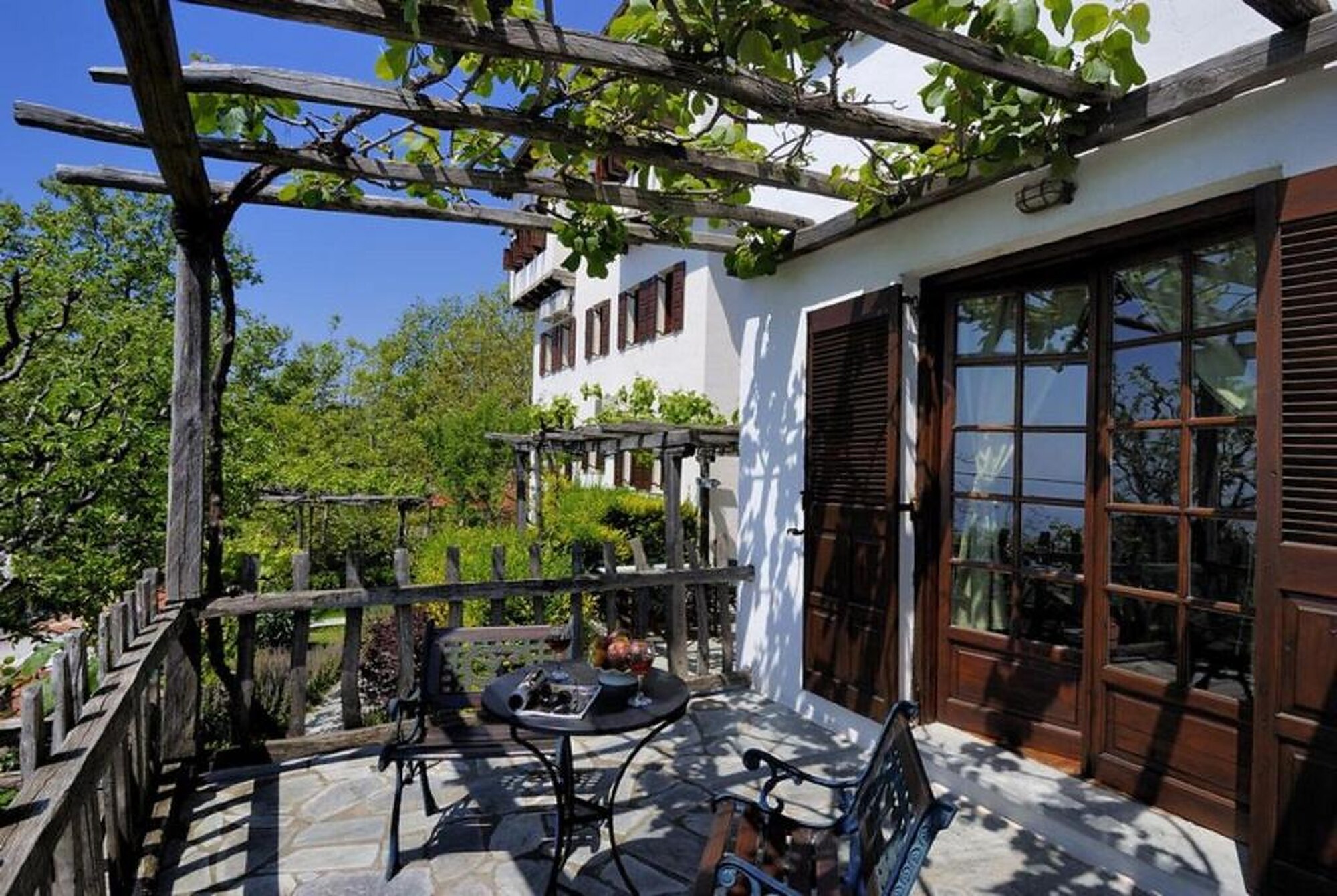 The vine-shaded stone terrace of Hotel Stoikos, with the mansion behind