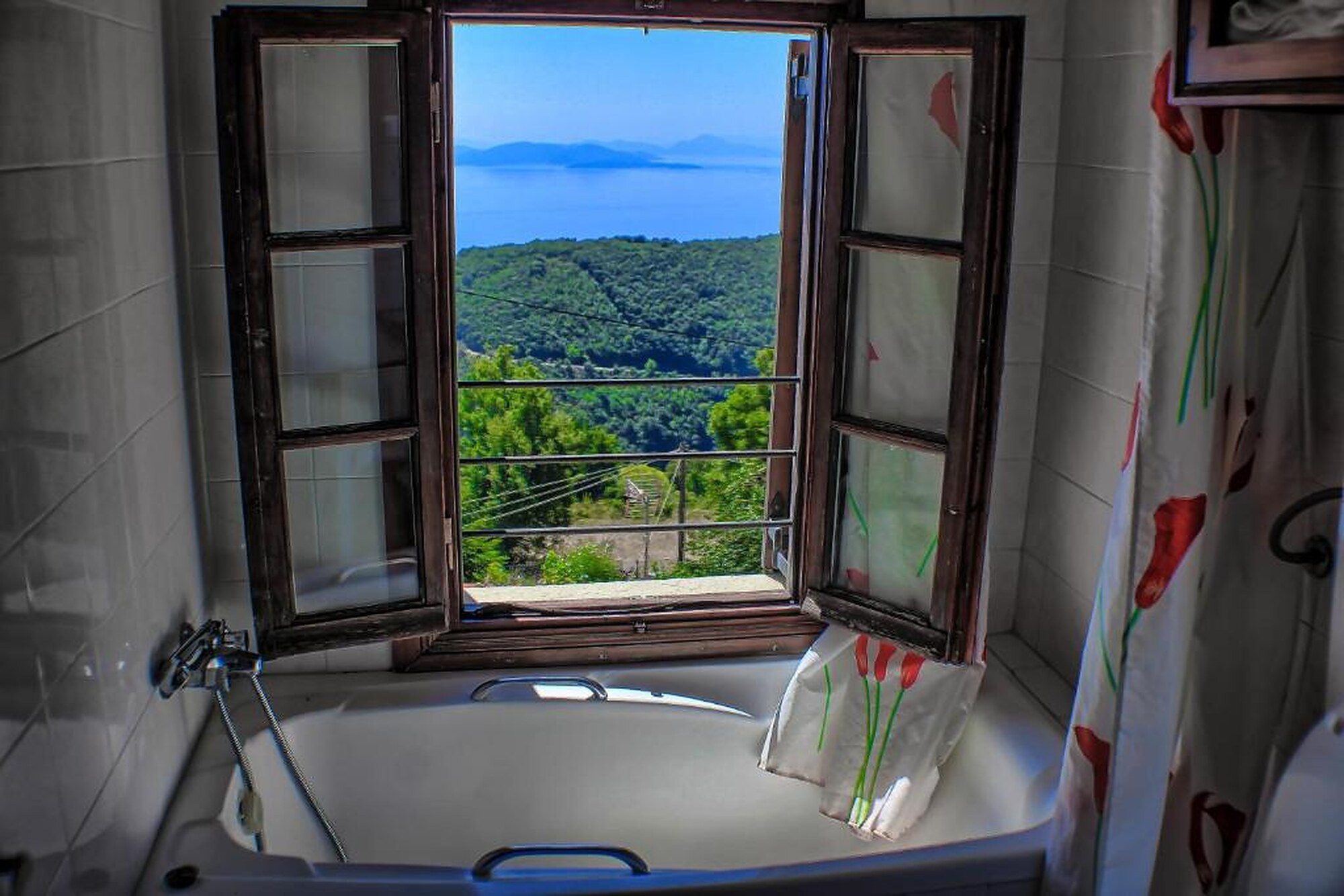 A room window framing the sea and forested slopes