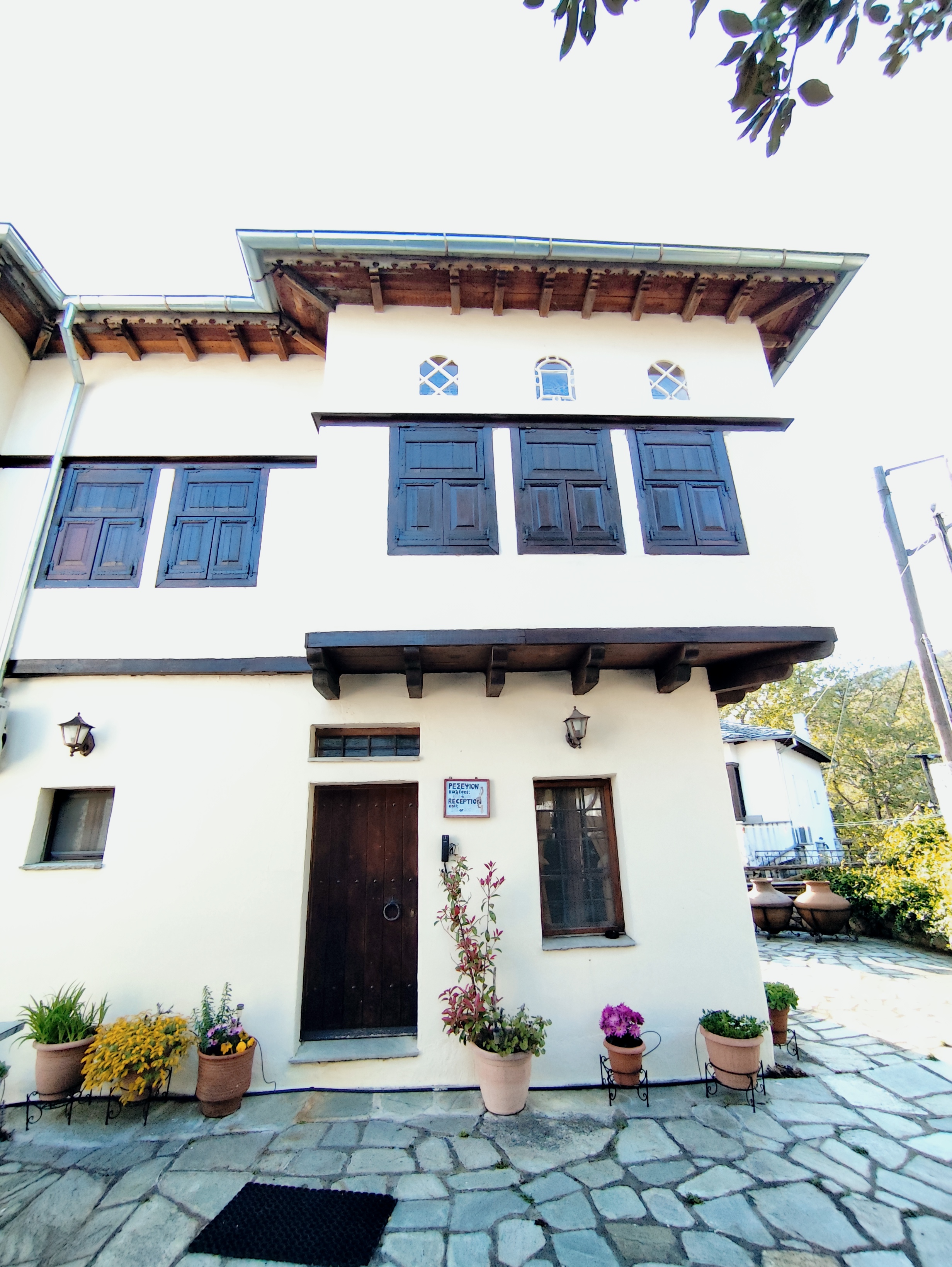 The traditional stone facade of Hotel Stoikos, with carved wooden shutters and the reception door