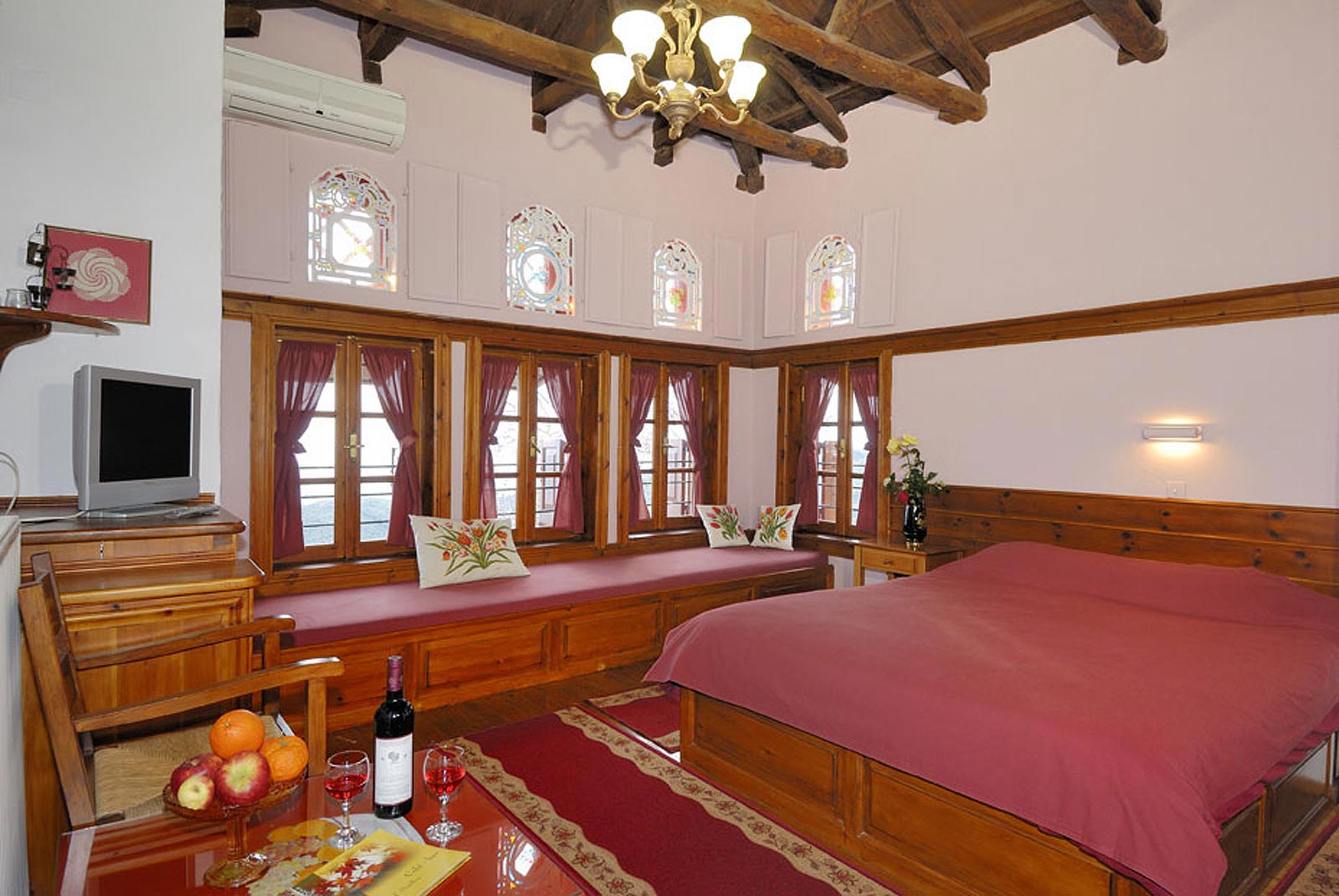 Traditional suite, exposed beam ceiling, painted windows, red bedspread